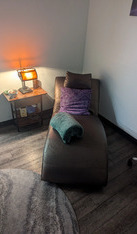 a psychologist's couch with pillows and a small table with a lamp